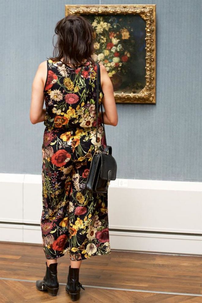 Женщина в платье в цветочек возле картины с цветами