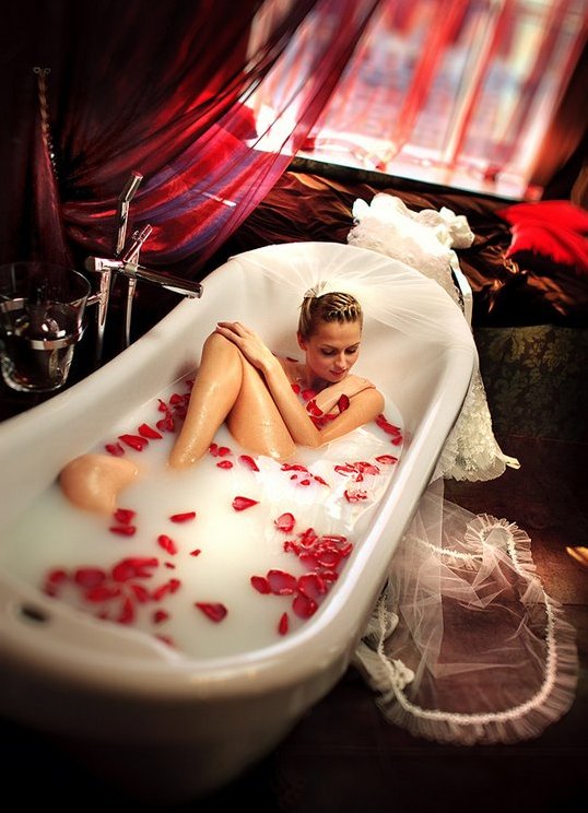 Прекрасная девушка в ванне с лепестками роз