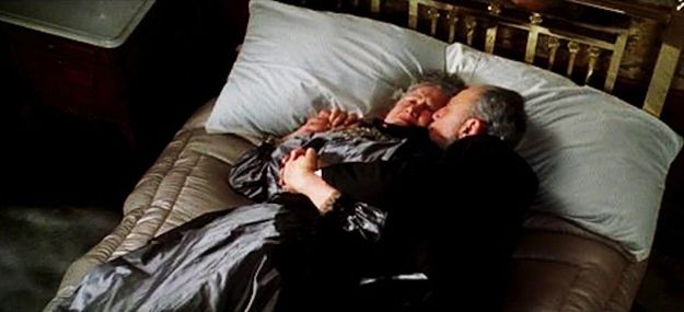 Пожилая пара, которая лежала, обнявшись на кровати