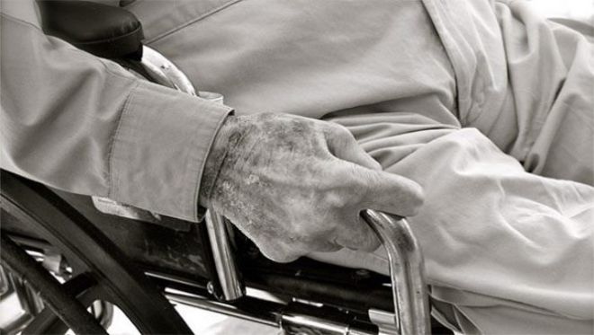 Старческая рука держится за инвалидную коляску