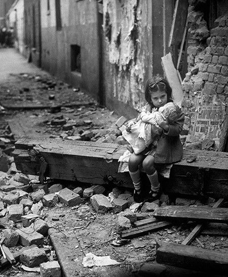 Девочка с куклой у разбомбленного дома