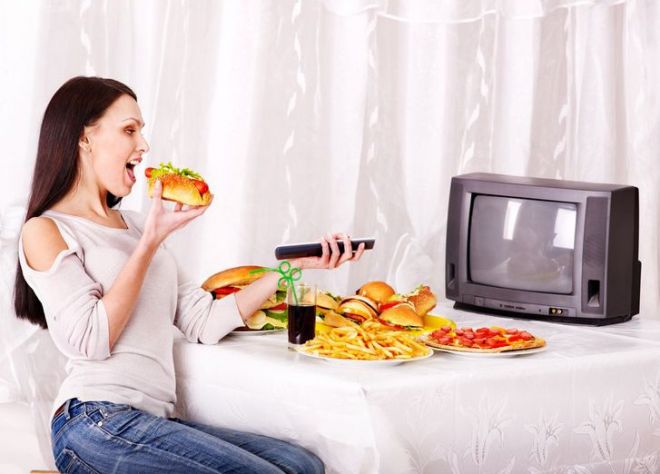 Девушка ест перед телевизором