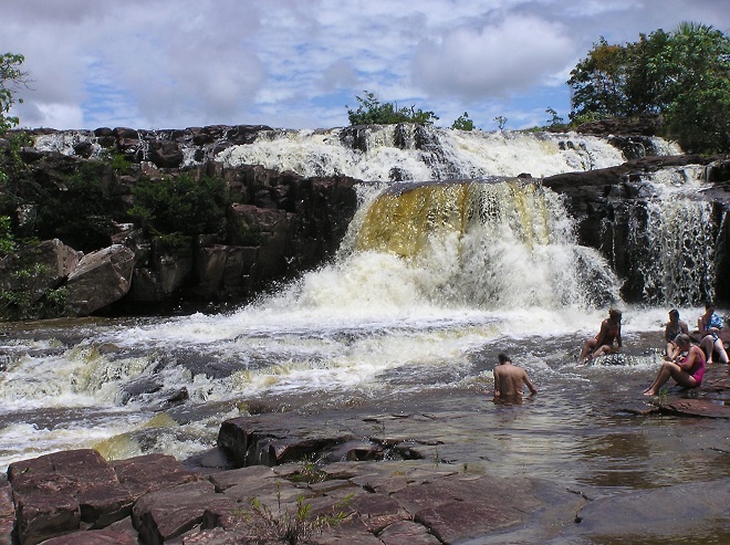 Туристы, купающиеся у подножья водопада